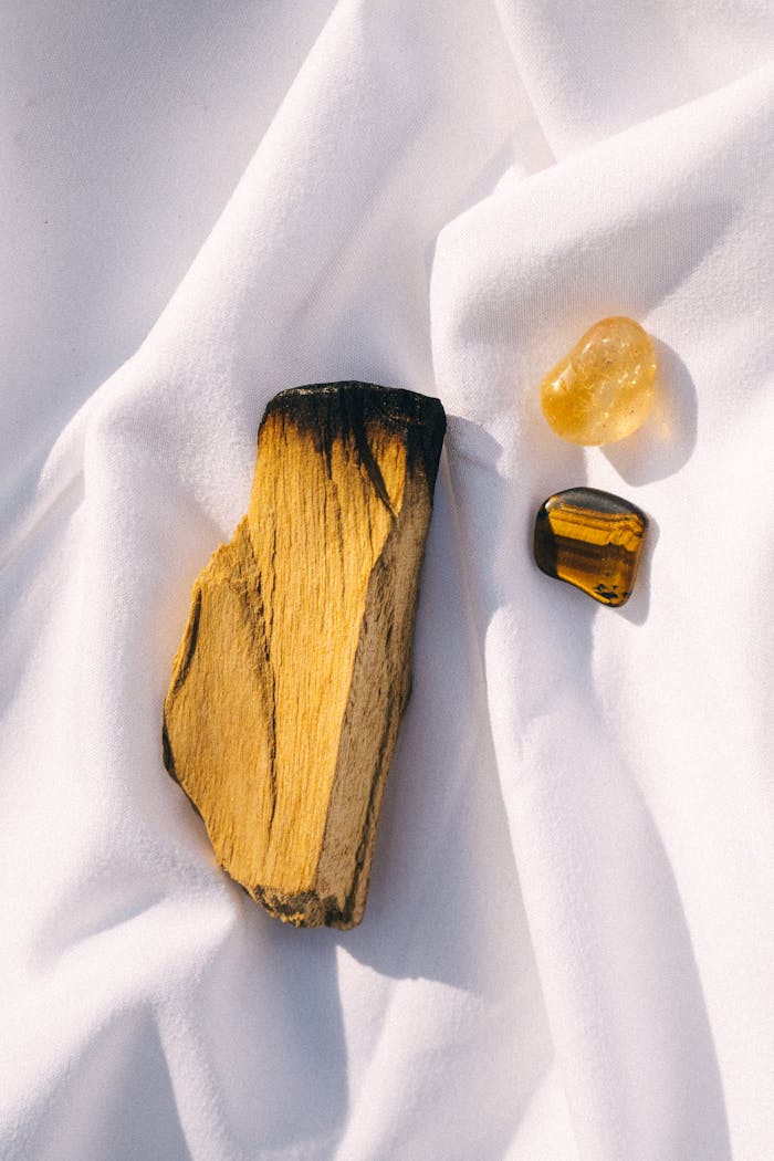 Arrangement of palo santo and crystals on white fabric for smudging rituals.